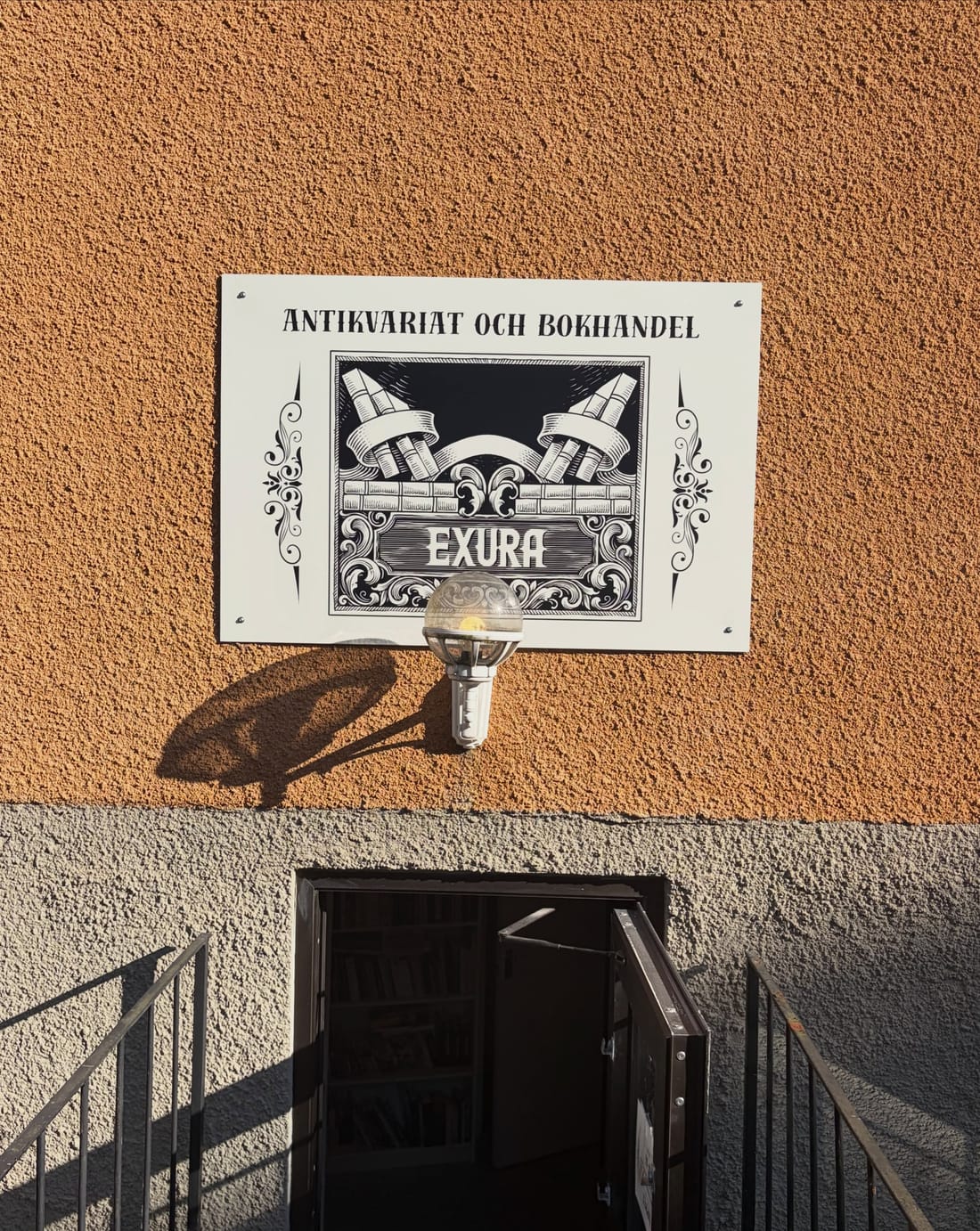Skylten Antikvariat och bokhandel ovanför trappan ner till butiken